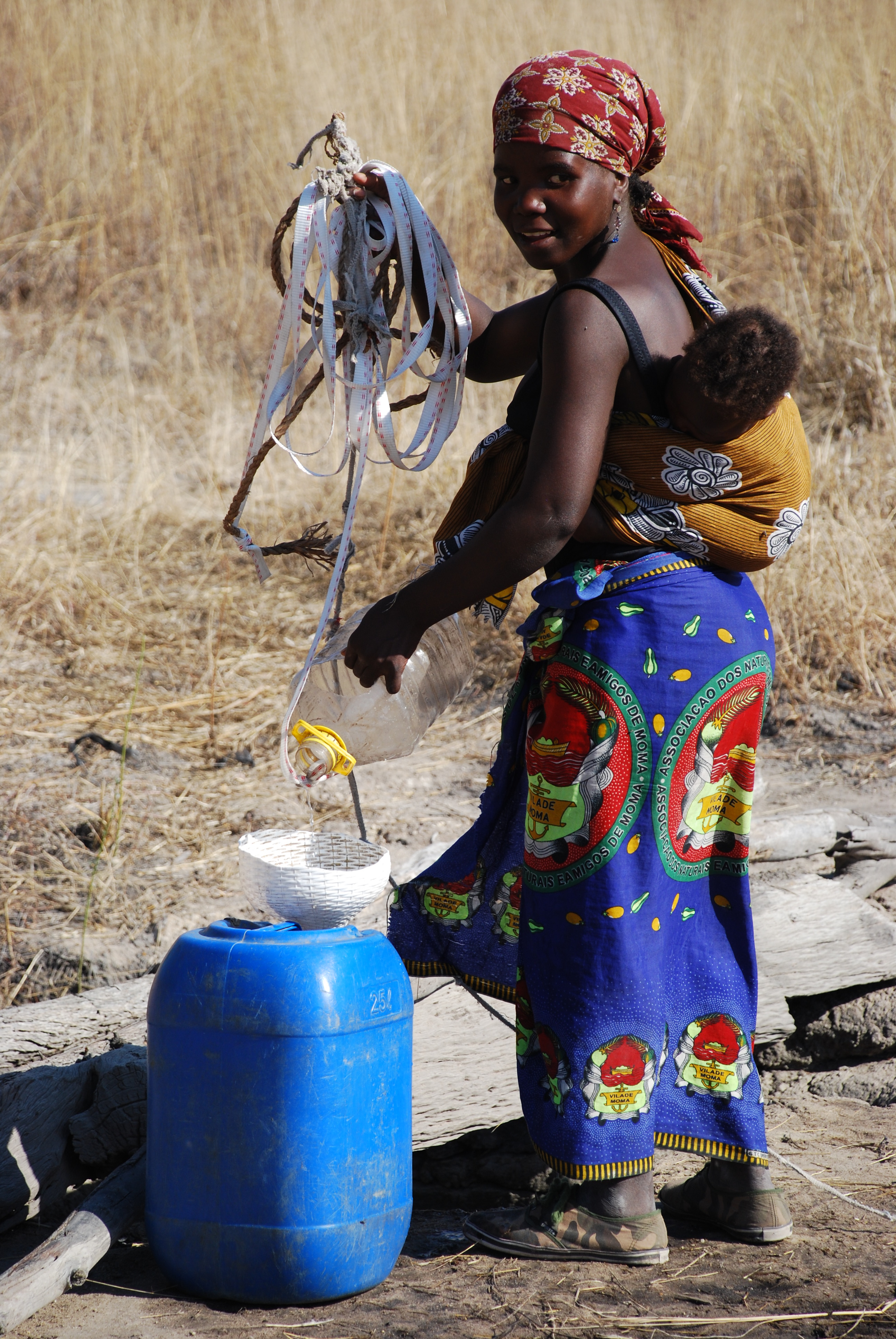 Woman with baby at local water well, Zambia.