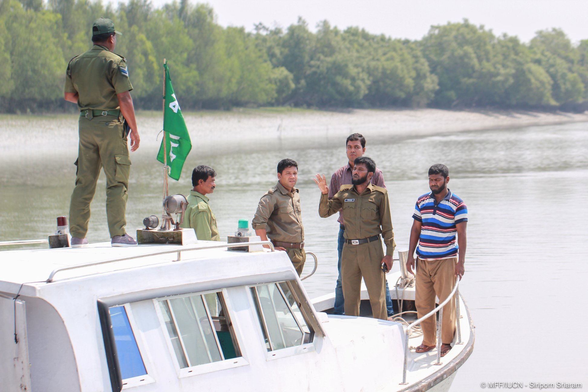 Several park rangers stand on a boat in the Sundarbans