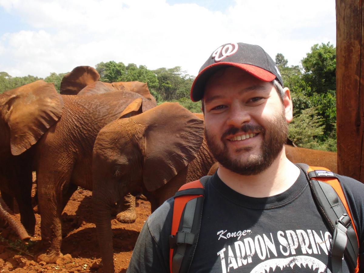 man with dirt covered elephants behind him