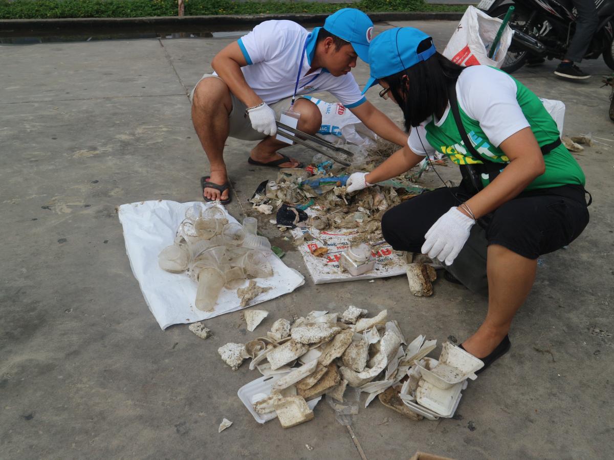 Two volunteers sort scraps of plastic, styrofoam and miscellaneous waste on the beach