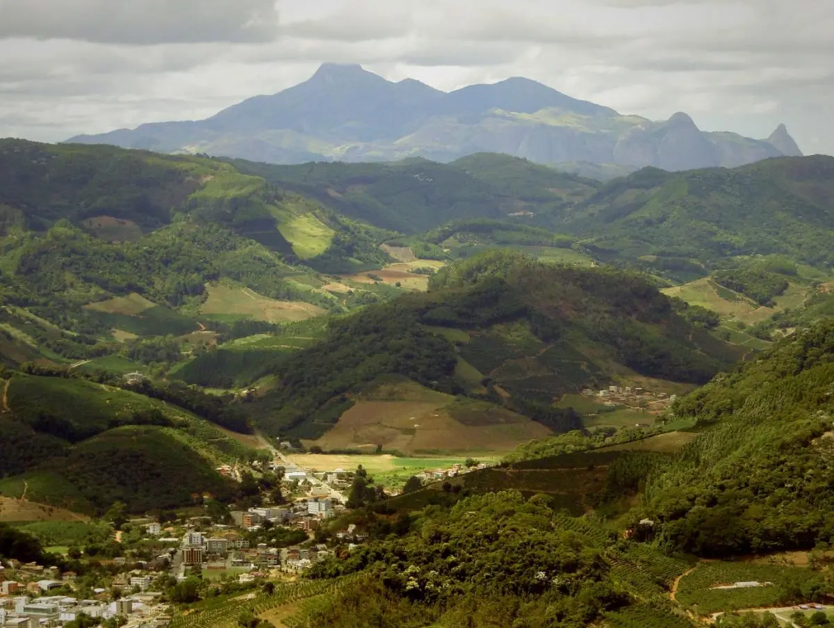 verdant landscape with hills, a town in the foreground and mountain in the back