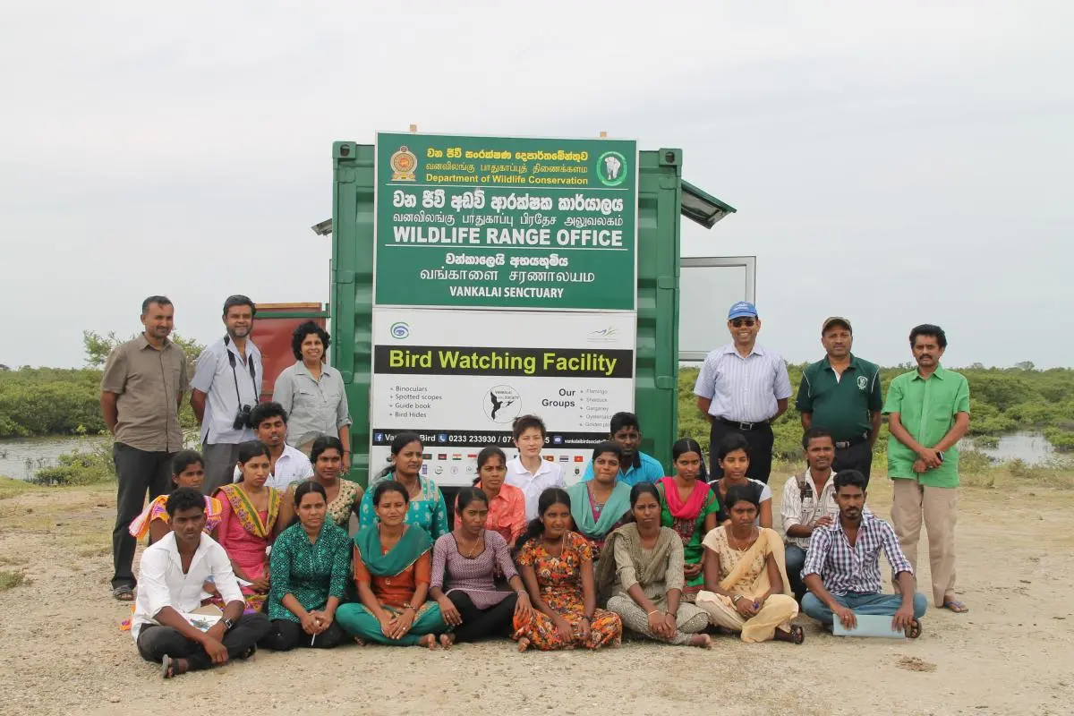 Group photo on a beach in front of the Wildlife Range Office sign