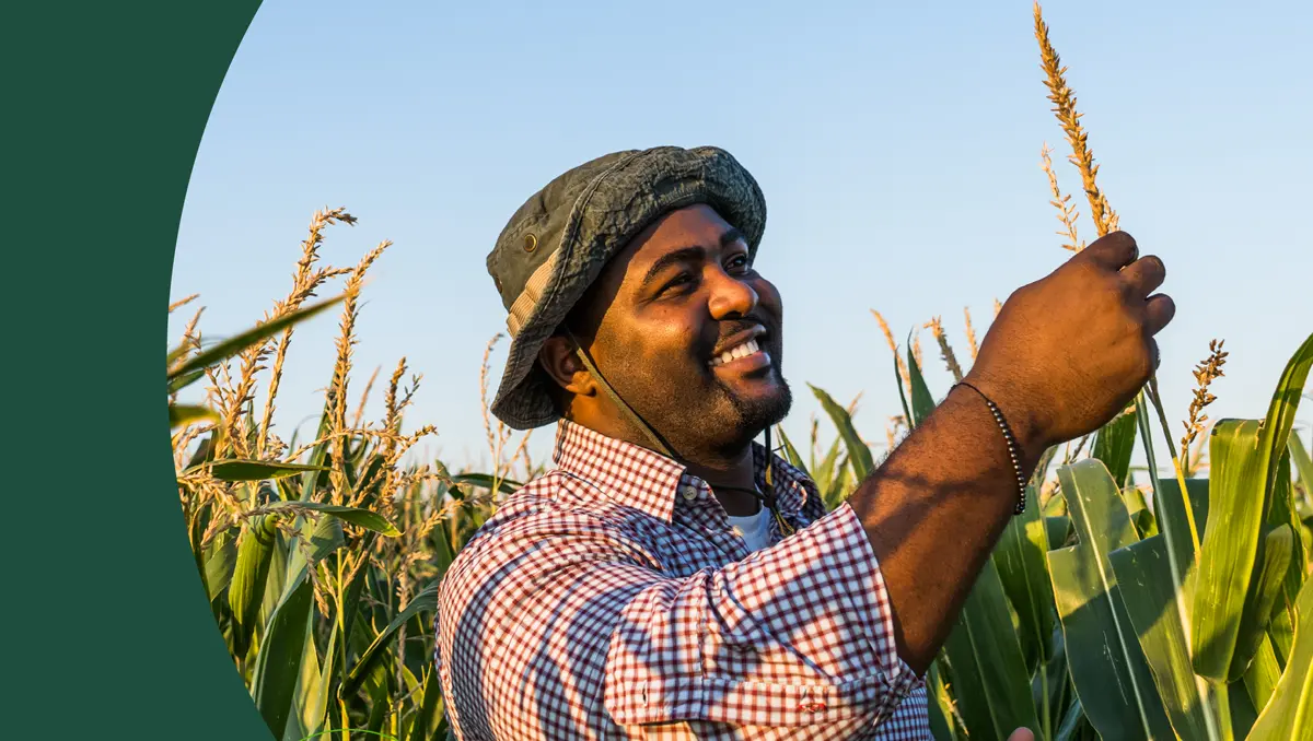 man holding grain stalk and smiling